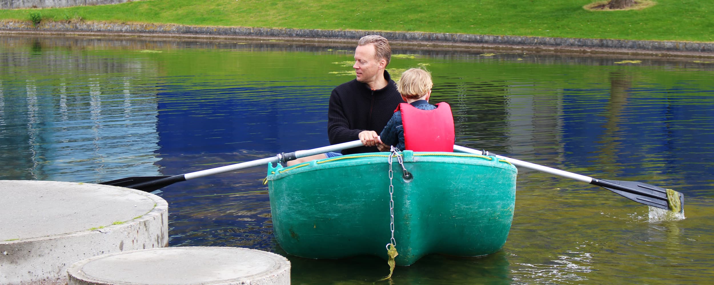 Far og søn ror en tur i en af Vandlaugets både i Den Landskabelige Kanal på Grønningen i Ørestad Nord. Refleksionen af DR Koncerthuset skimtes i vandspejlet.