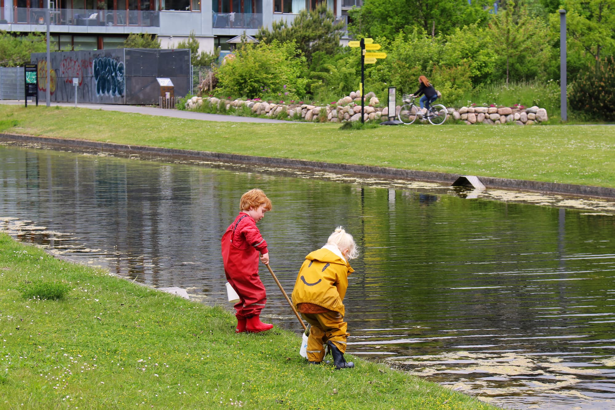 Naturdag i Ørestad Nord. To børn undersøger dyrelivet i Den Landskabelige Kanal på Grønningen ved hjælp af grej fra parkens Naturcontainer.