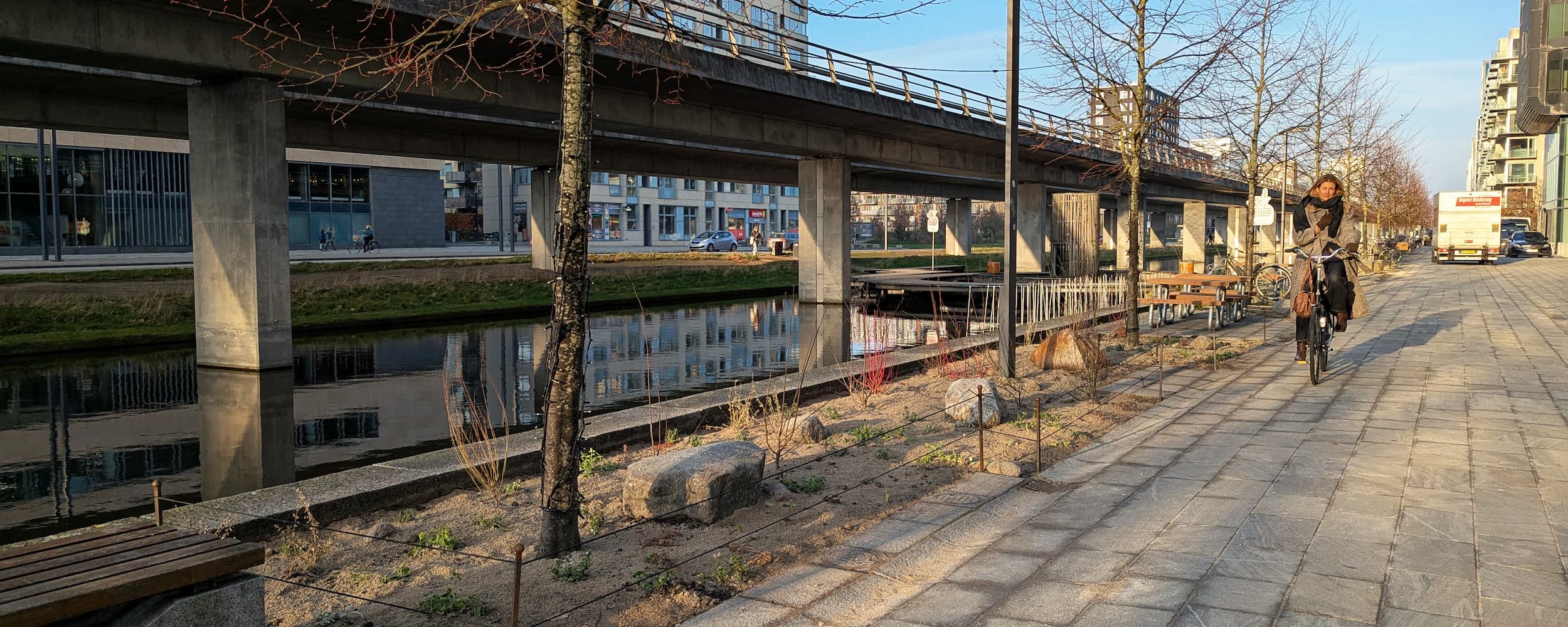 Et bredt samarbejde i Ørestad City har etableret et grønt byrum ved Ørestad Gymnasium og Skole. Langs kanalen er nogle fliser fjernet for at gøre plads til blomsterbede, mens nye bænke, stole og plantekummer indbyder til ophold.
