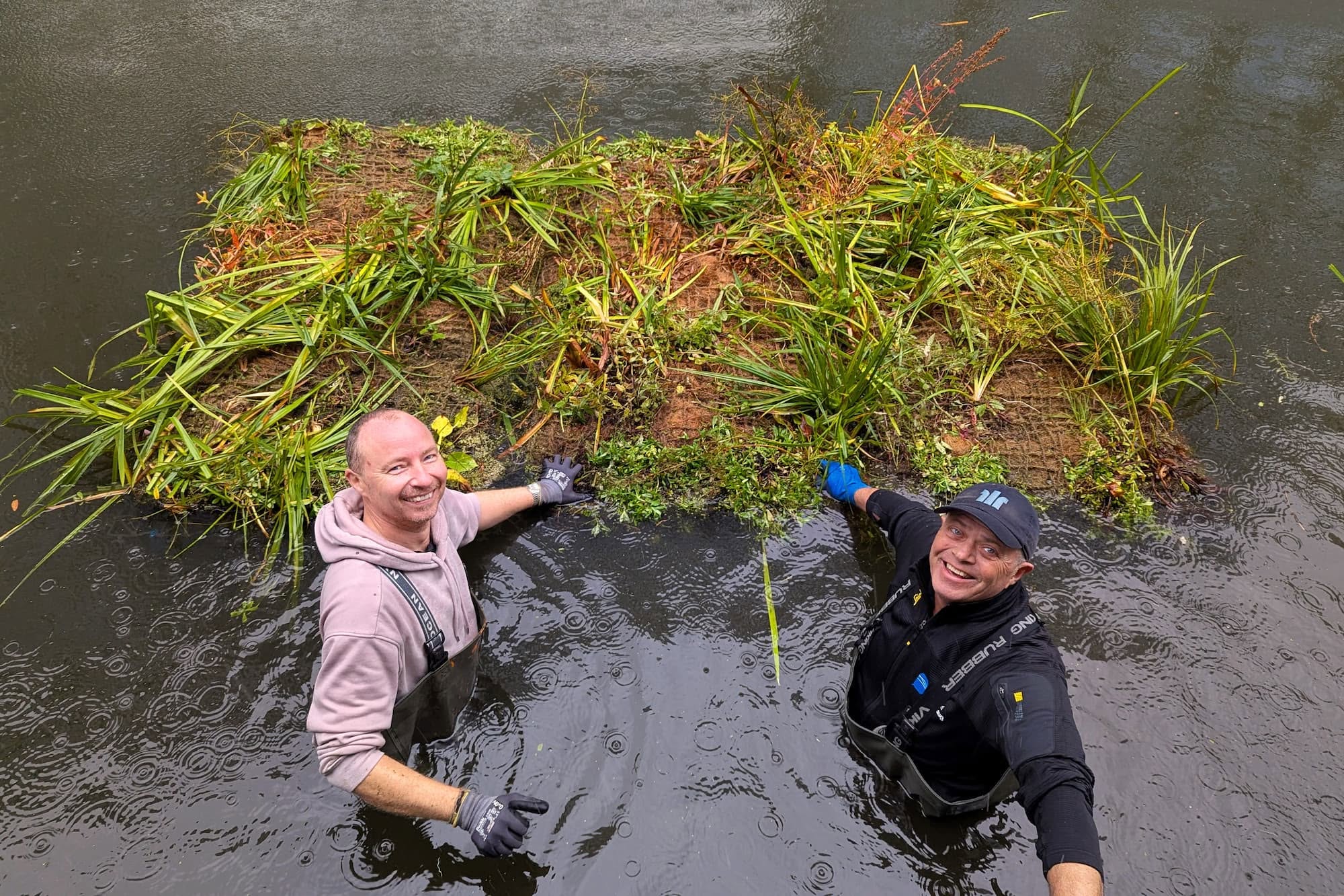 Grundejerforeningernes driftsansvarlige Jakob og Vandlaugets driftsassistent Kim er i vandet for at få en flydende plantemåtte til at ligge helt perfekt.